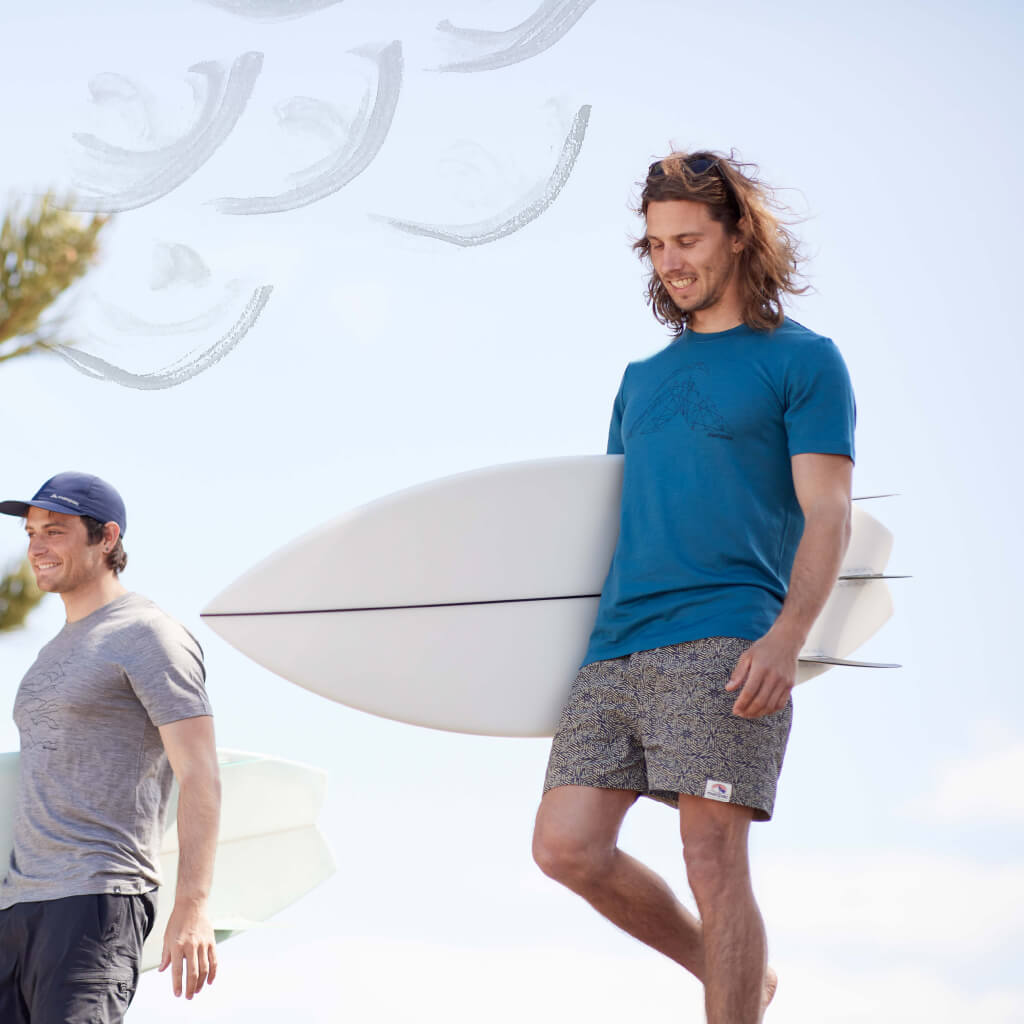 Man wearing Winger shorts carrying surfboard
