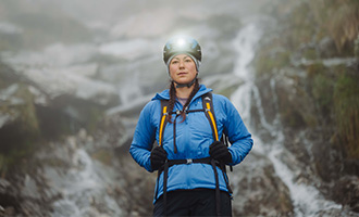 Person wearing bright blue jacket and alpine climbing gear with mountain background