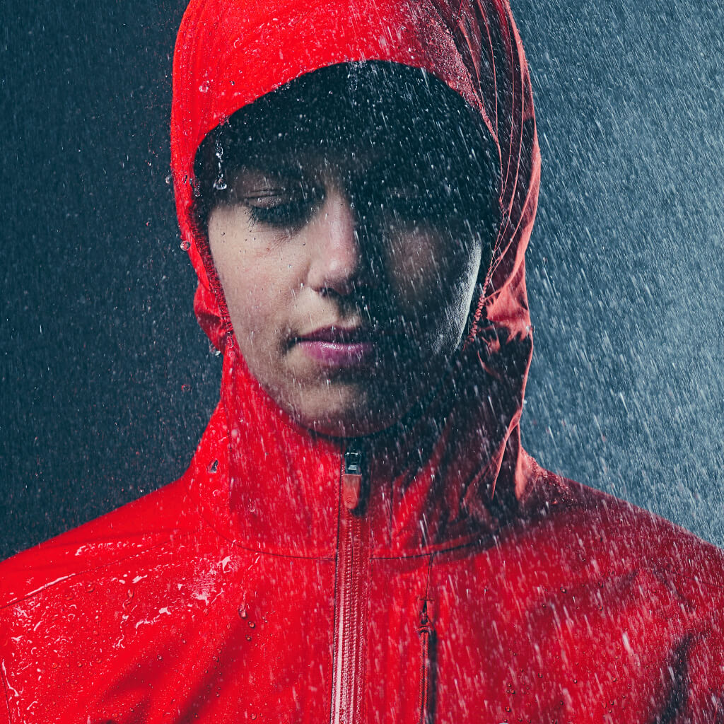 Person wearing red hooded Tempo Jacket with heavy rain dripping off hood