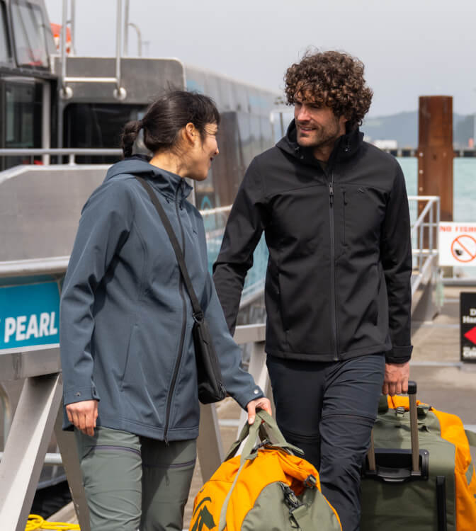 Man and woman getting off boat wearing softshell jackets