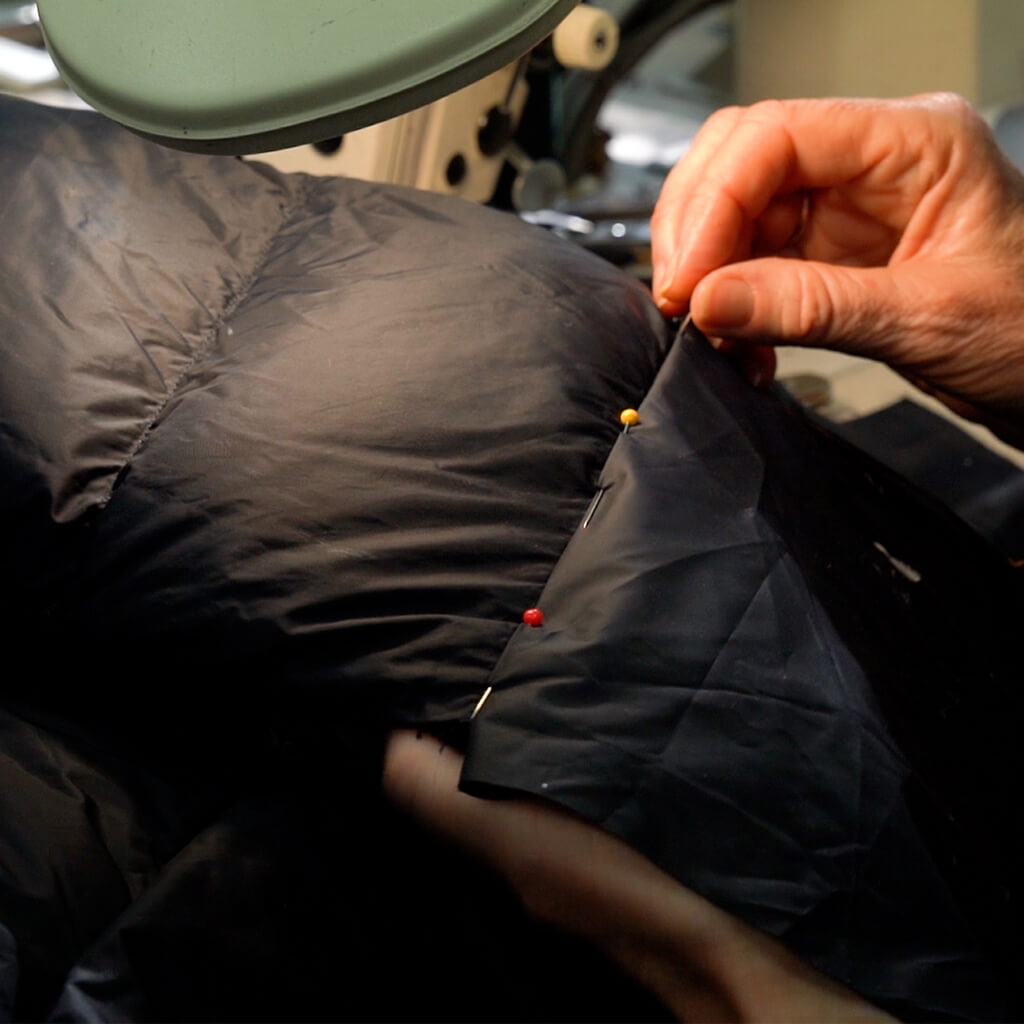 close up of down jacket baffle being replaced and pinned into place