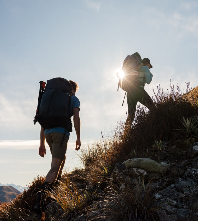 Silhouette of 2 hikers walking up steep hill
