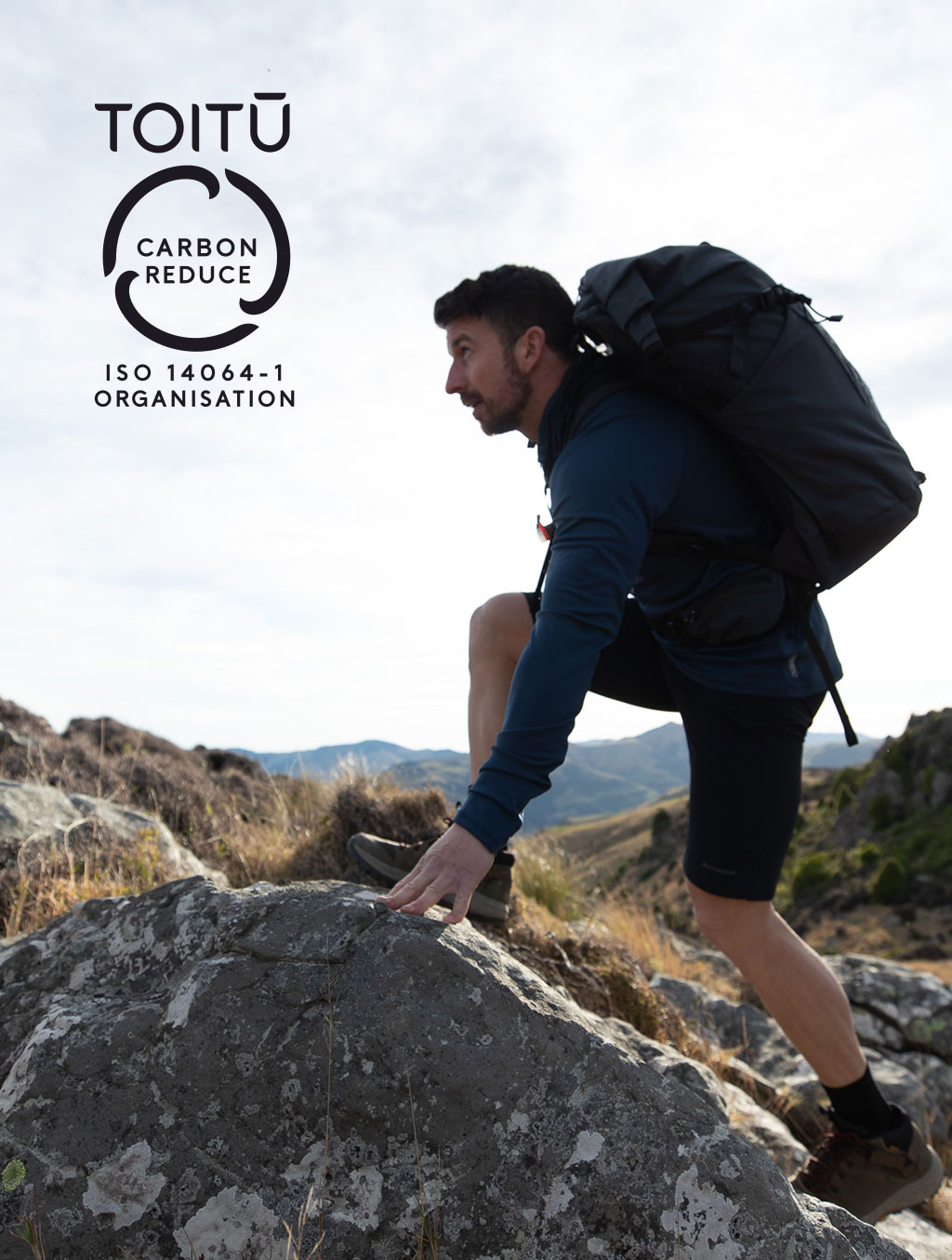 Man climbing over rock wearing hiking backpack - Toitu logo, carbon reduce ISO 14064-1 ORGANISATION
